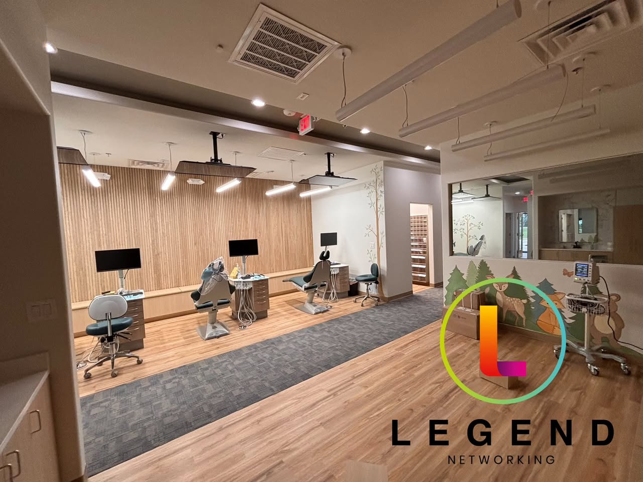Open pediatric treatment bay with dental chairs and monitors at Argyle Pediatric Dentistry.