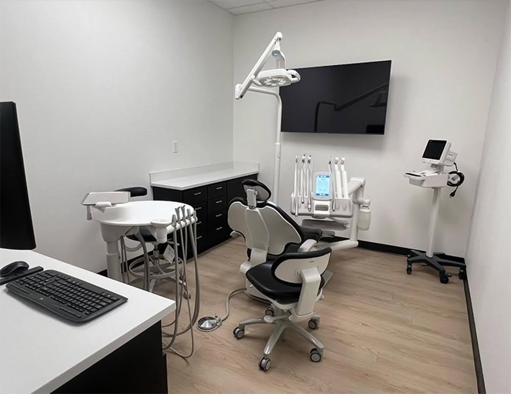 Dental chair, monitors and keyboard in a Dental Plus Specialists operatory.