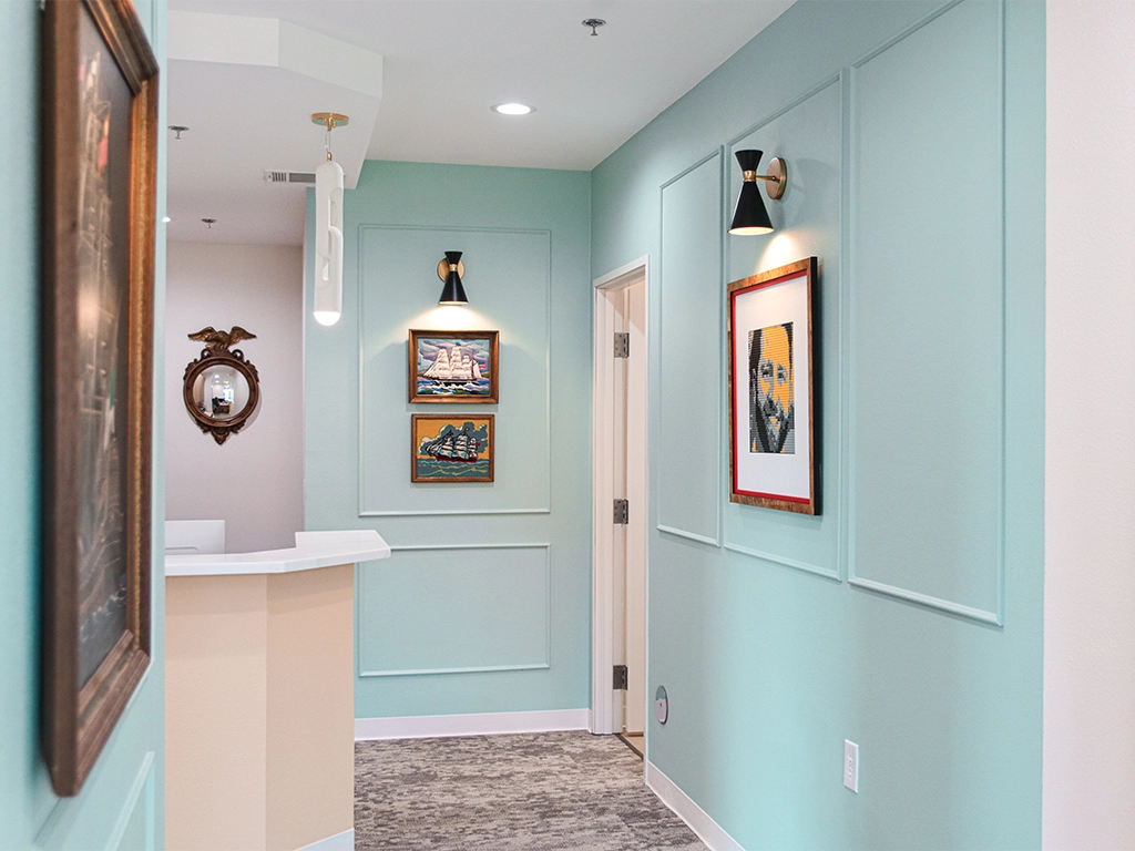Happy Harbor Pediatric Dentistry hallway with aqua walls, framed art and treatment room doorways.
