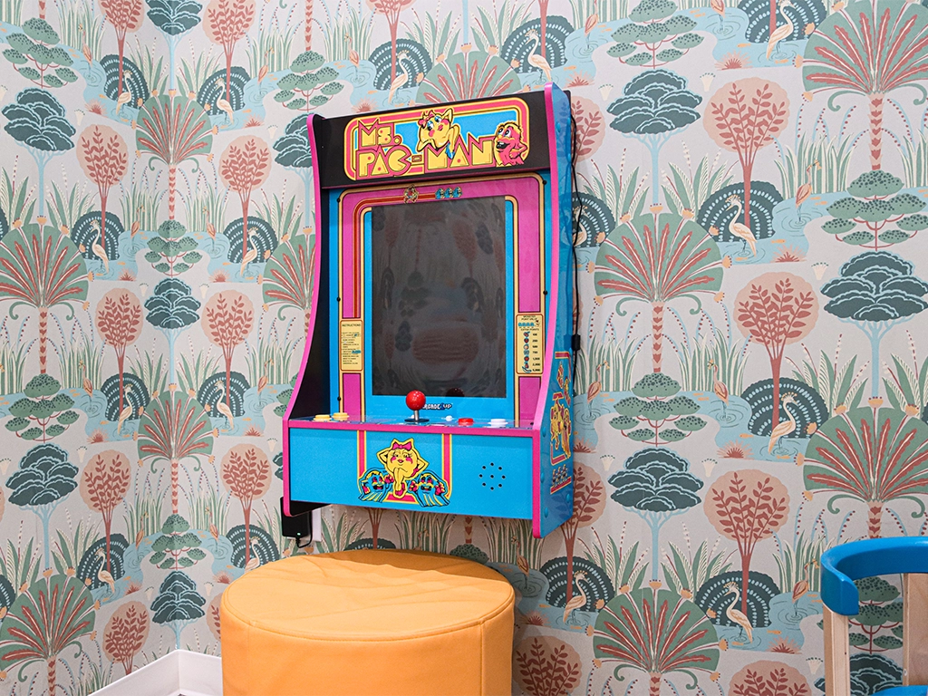 Children’s arcade area at Happy Harbor Pediatric Dentistry with a wall-mounted Ms. Pac-Man game and illustrated wallpaper.