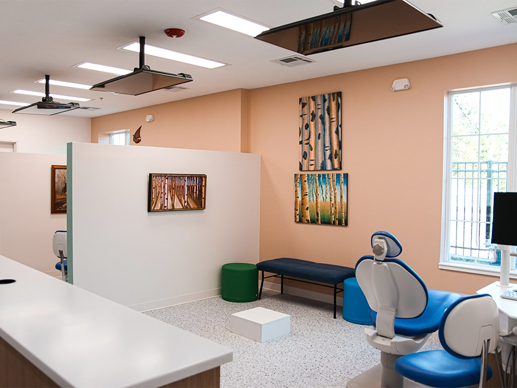 Open treatment area at Happy Harbor Pediatric Dentistry with blue dental chairs and peach-colored walls.