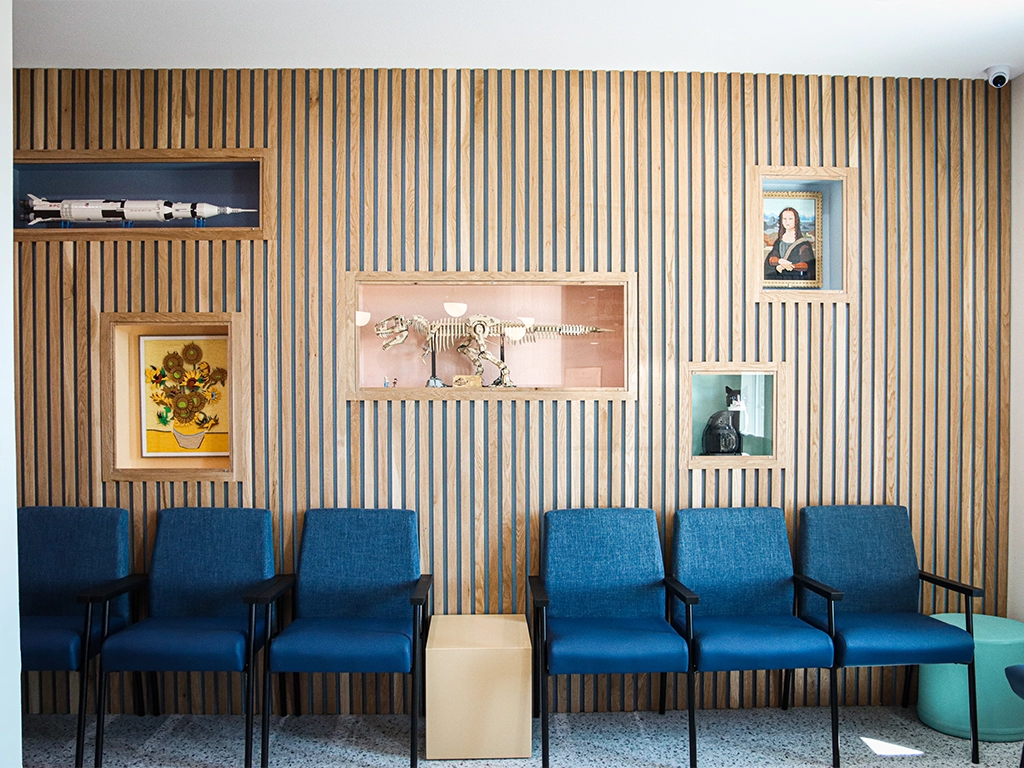 Happy Harbor Pediatric Dentistry waiting room with blue chairs, wood slat walls and nautical artwork.