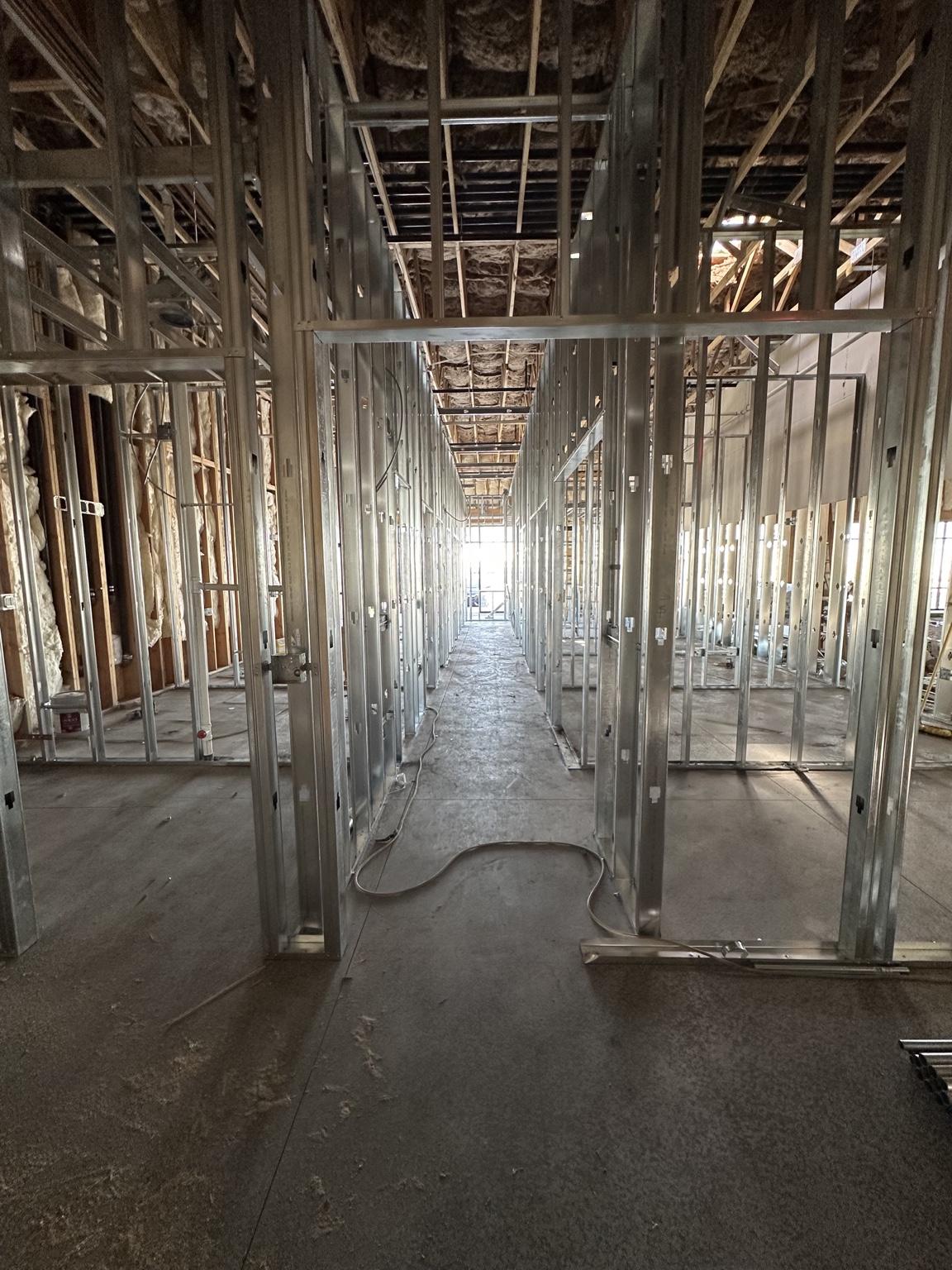 Haven Dental corridor during construction with framed treatment rooms and exposed ceiling insulation.