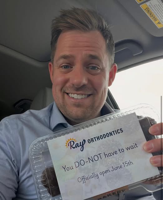 Dr. Andrew Ray holding a Ray Orthodontics opening announcement dated June 15.