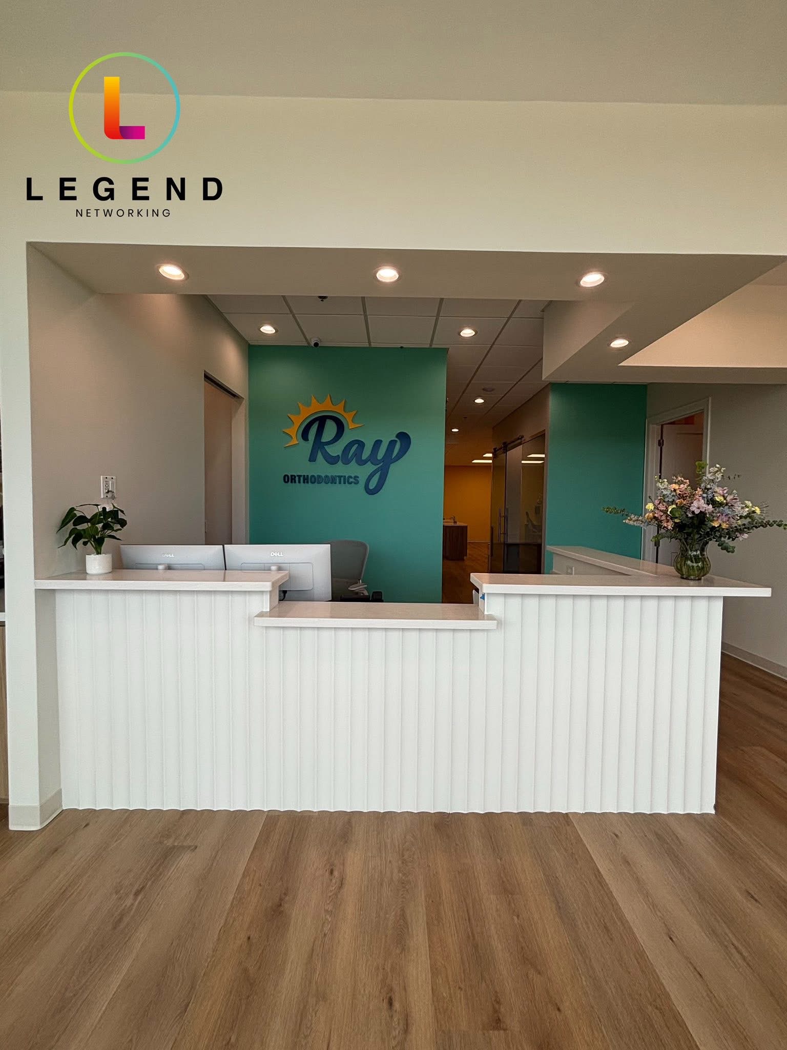 Front view of the Ray Orthodontics reception desk with two workstations and the practice logo.