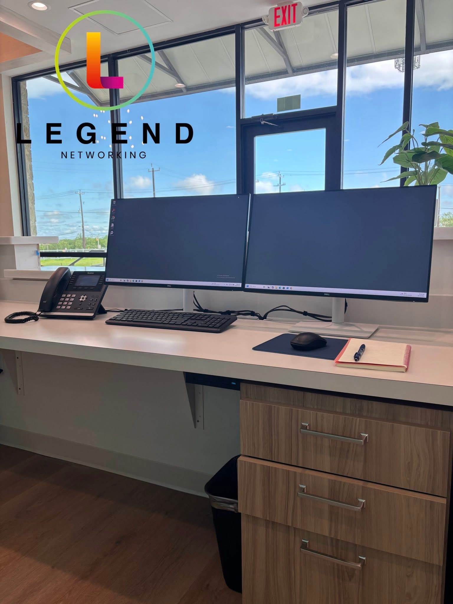 Close view of a Ray Orthodontics workstation with two monitors, keyboard, mouse and desk phone.
